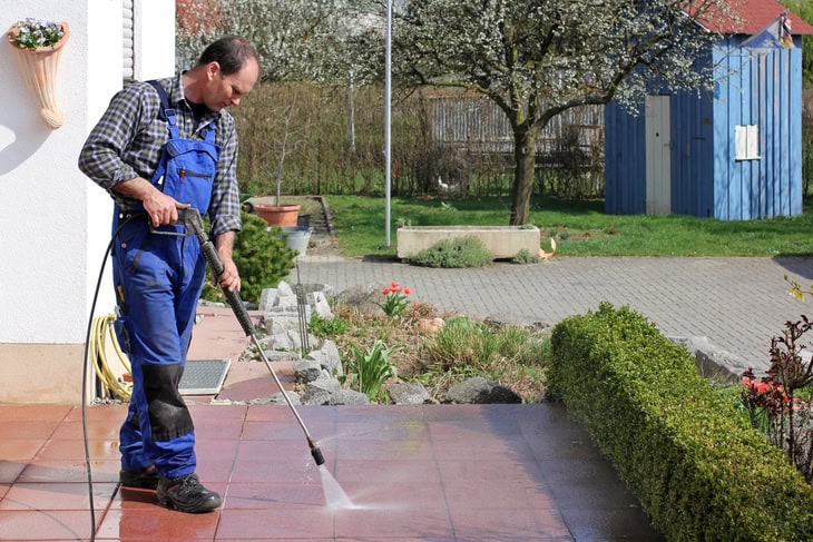 Man cleaning his terrace with his high powered pressure washerMan cleaning his terrace with his high powered pressure washer